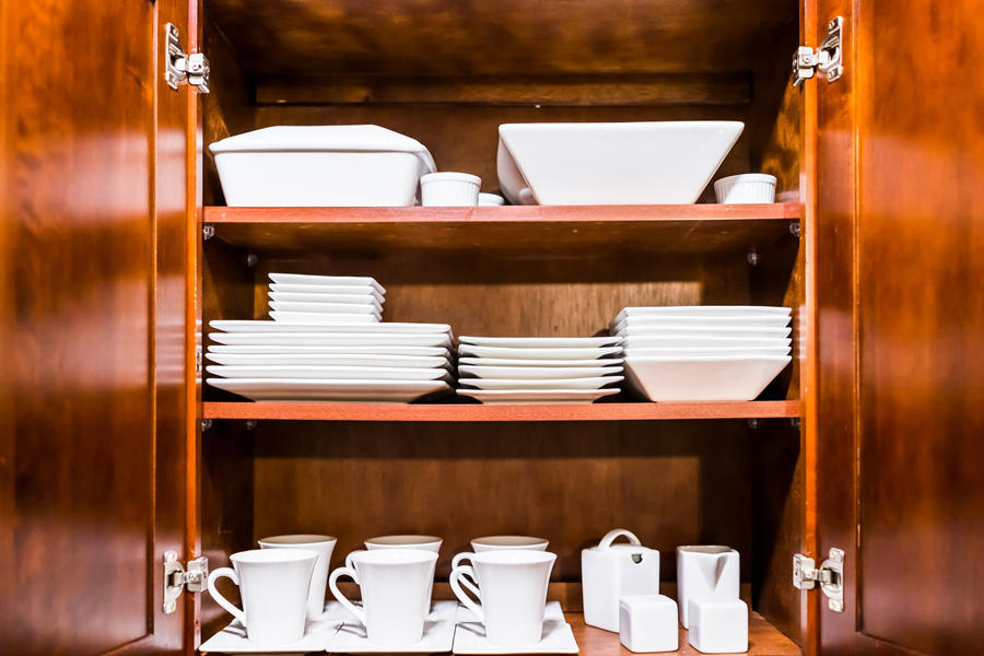 A clean, organised crockery cupboard in a kitchen.